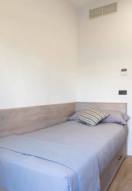 Detalle cama en habitación individual en residencia universitaria en Madrid